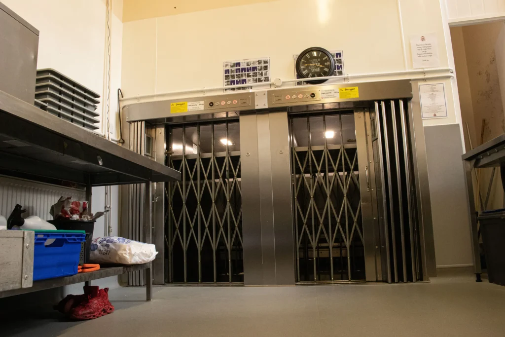 Two goods lifts are situated side by side to help move heavy and bulky items between floors.